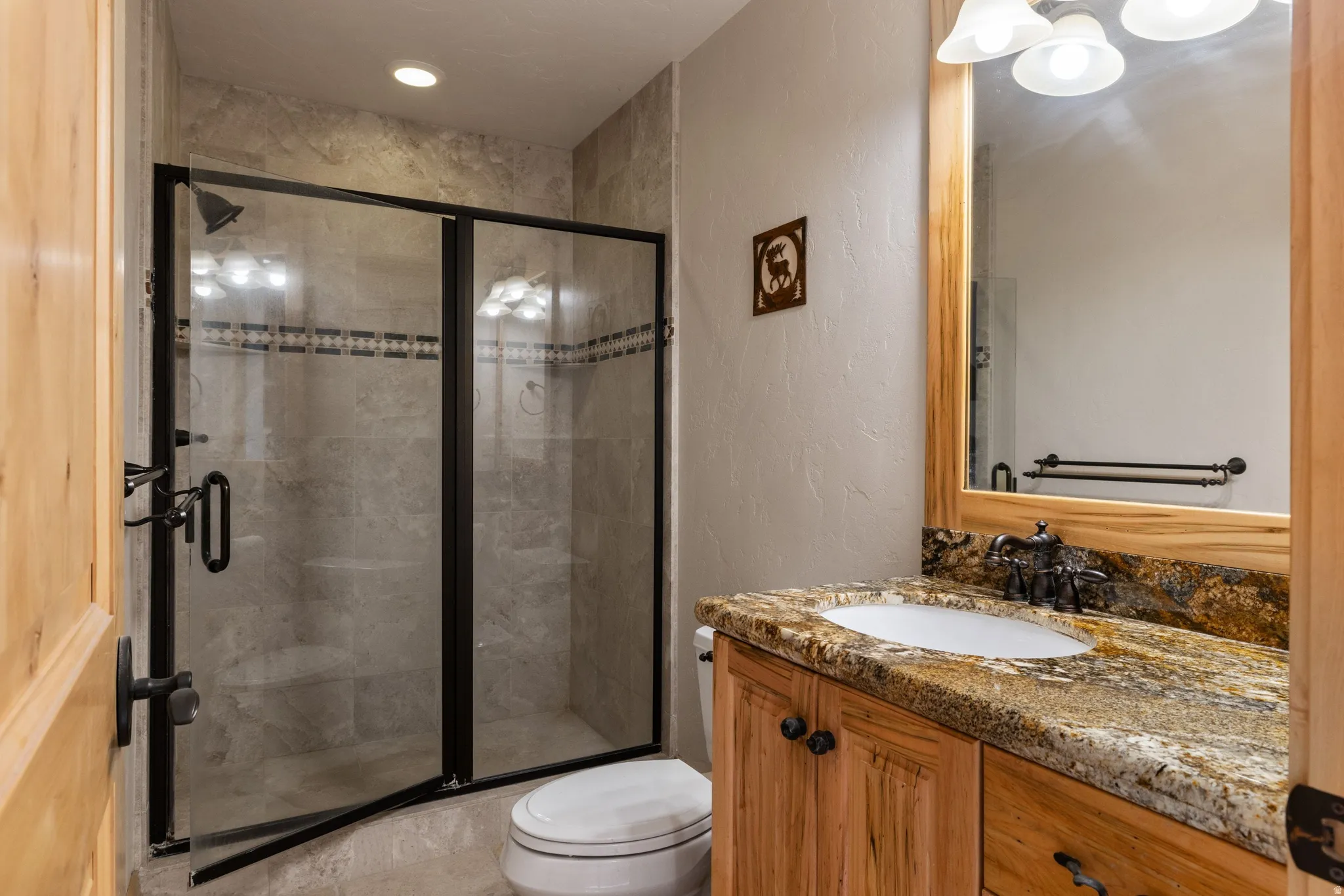 Bathroom featuring a textured wall, vanity, and a shower stall