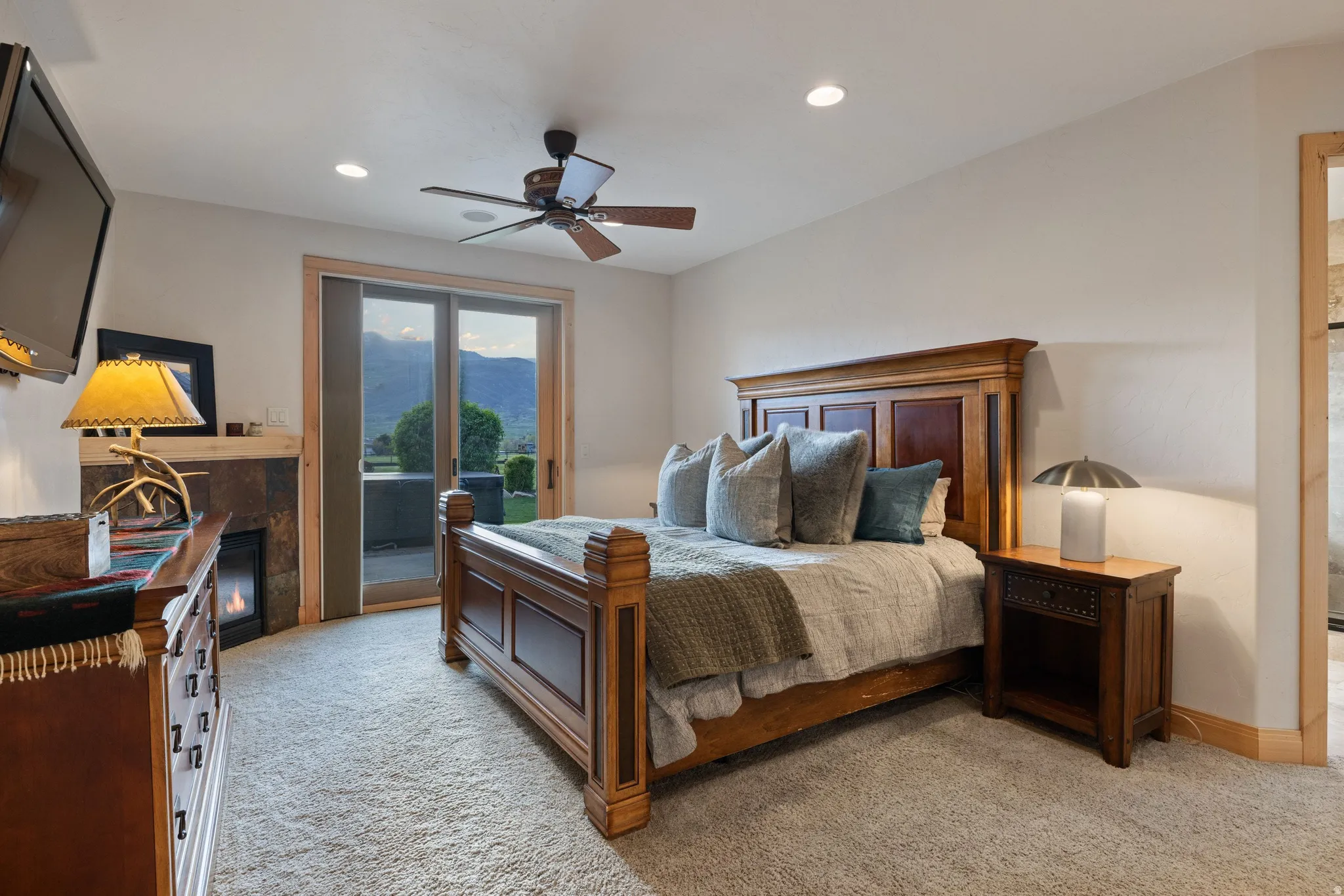 Bedroom featuring light carpet, ceiling fan, a tiled fireplace, recessed lighting, and access to outside