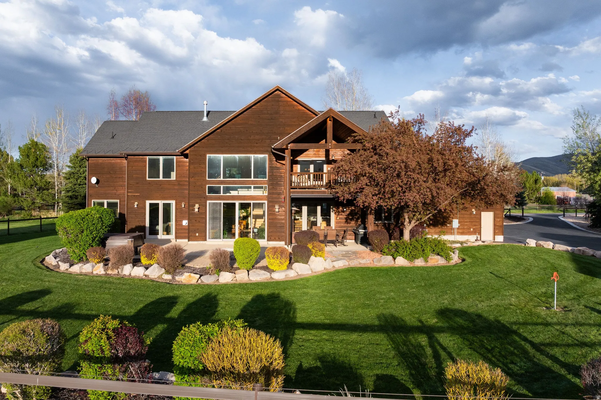 Rear view of house featuring a patio area, a balcony, and a lawn