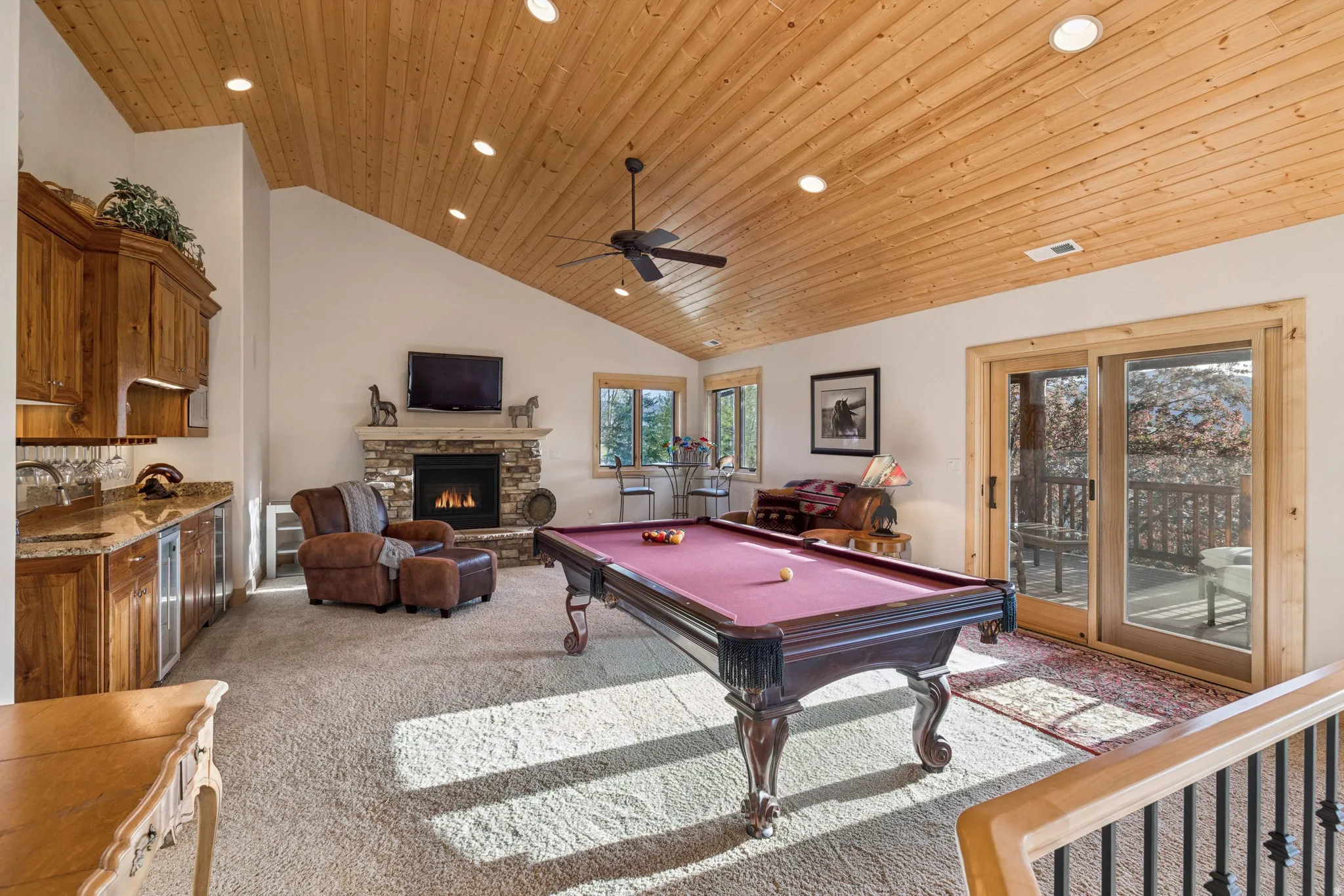 Rec room featuring a vaulted wooden ceiling, light carpet, a fireplace, ceiling fan, and billiards