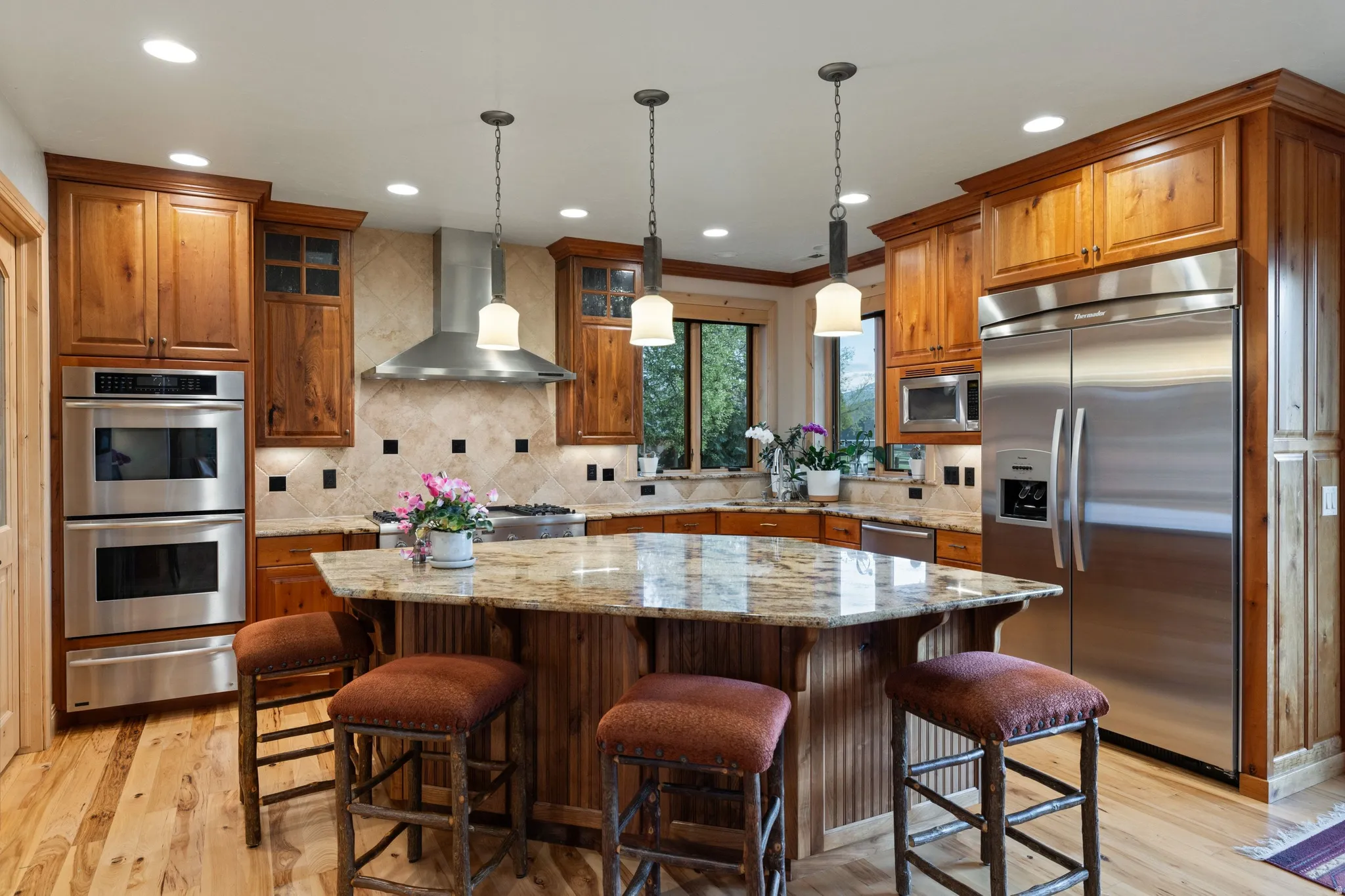 Kitchen featuring built in appliances, light stone countertops, a center island, tasteful backsplash, and wood finish cabinetry