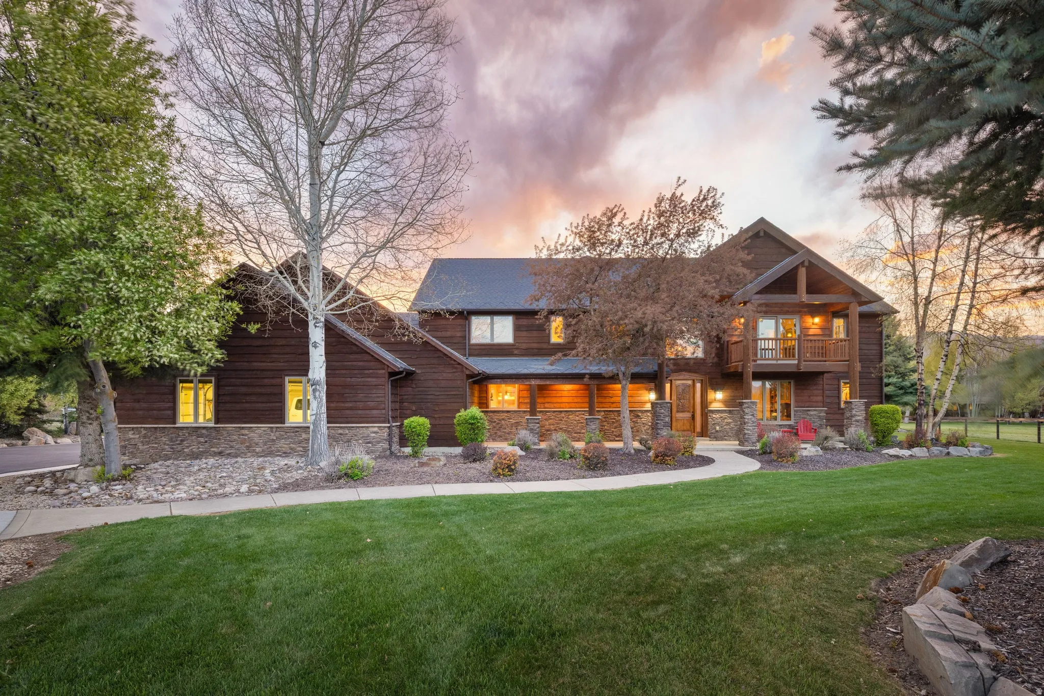 View of front of house with a front lawn, stone siding, and a balcony