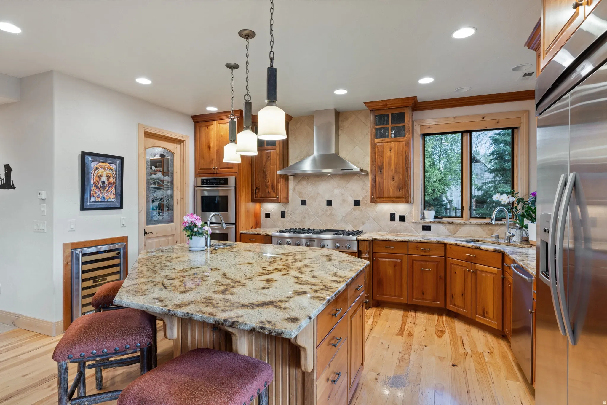 Kitchen with stainless steel appliances, a kitchen breakfast bar, wood finish cabinets, and light wood finished floors