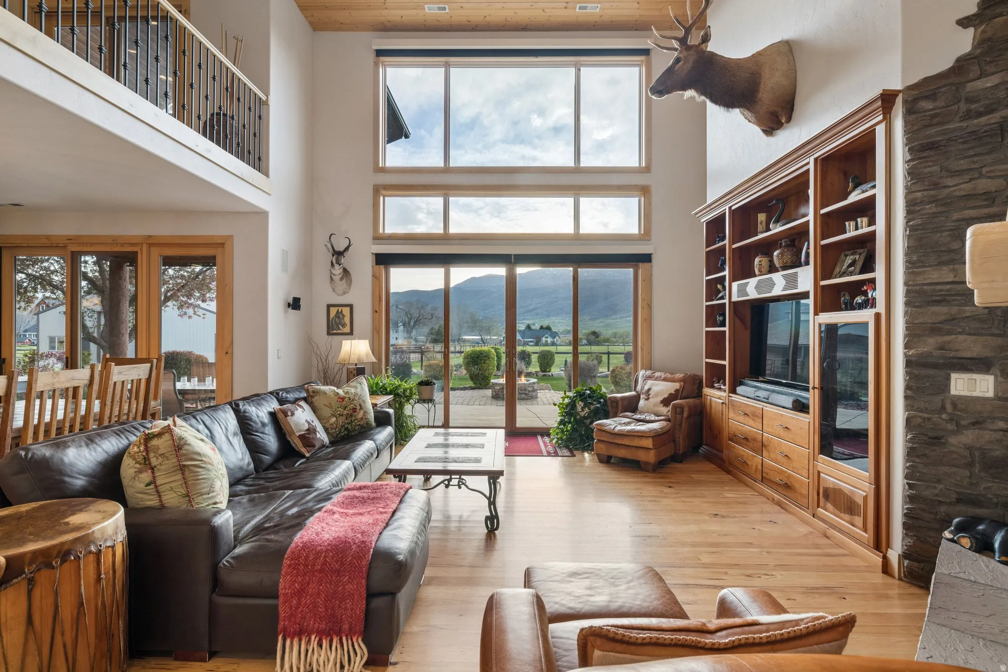Living room with a high wooden ceiling, light wood-style floors, and healthy amount of natural light
