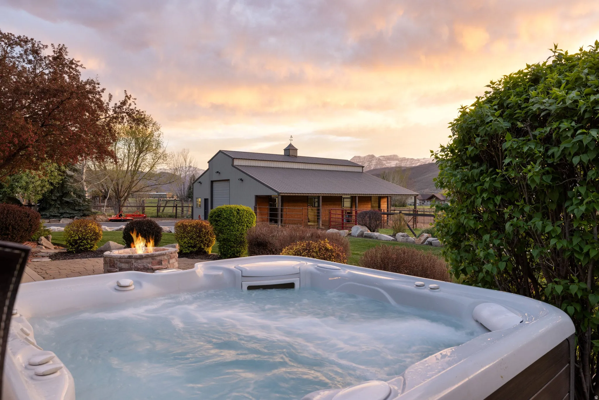 View of front of property with a hot tub, a chimney, an outdoor fire pit, a metal roof, and an outbuilding