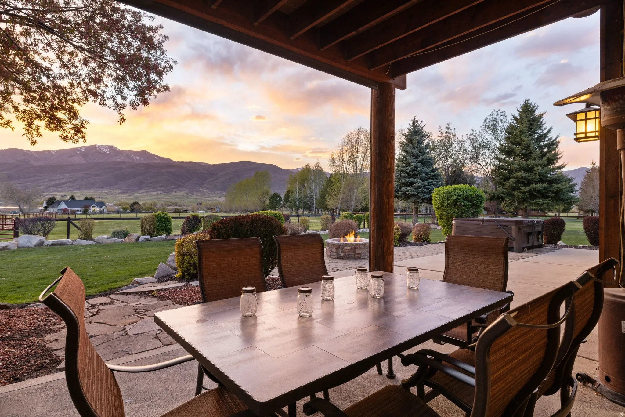 Patio terrace at dusk with a patio, a fire pit, outdoor dining area, a mountain view, and a yard