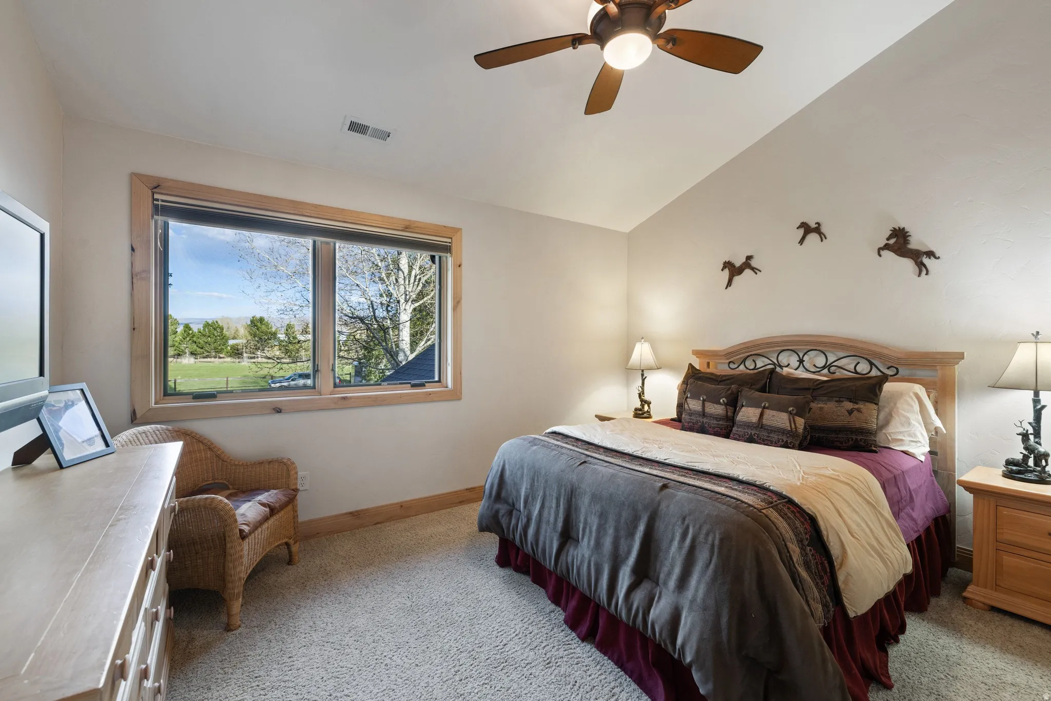 Bedroom featuring light colored carpet, vaulted ceiling, and ceiling fan