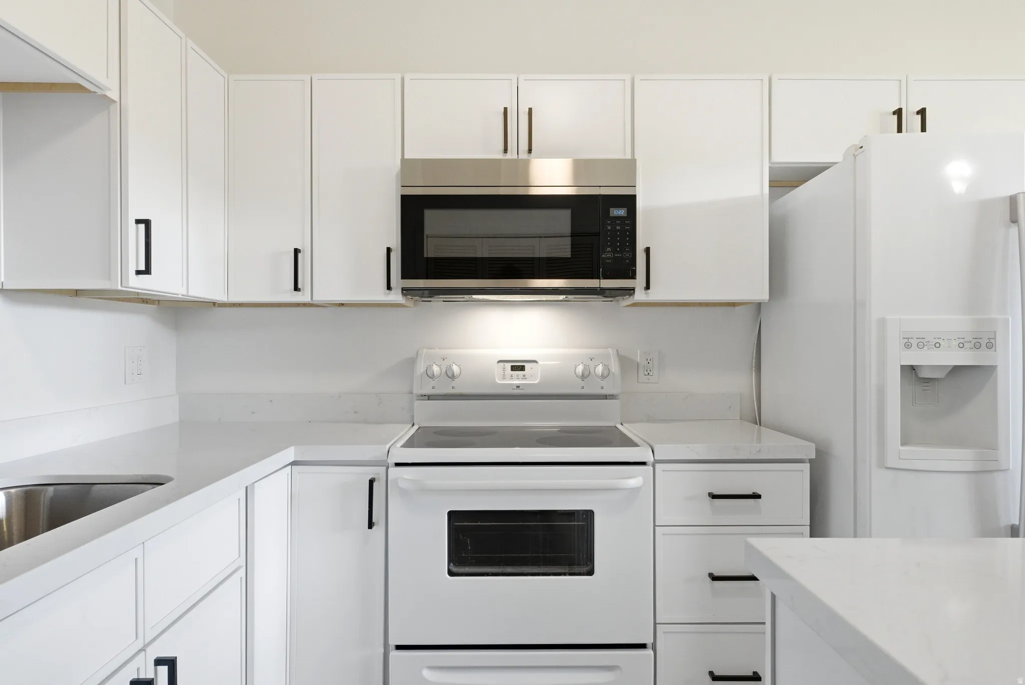 White kitchen featuring an over-the-range microwave, electric range, and matching white refrigerator