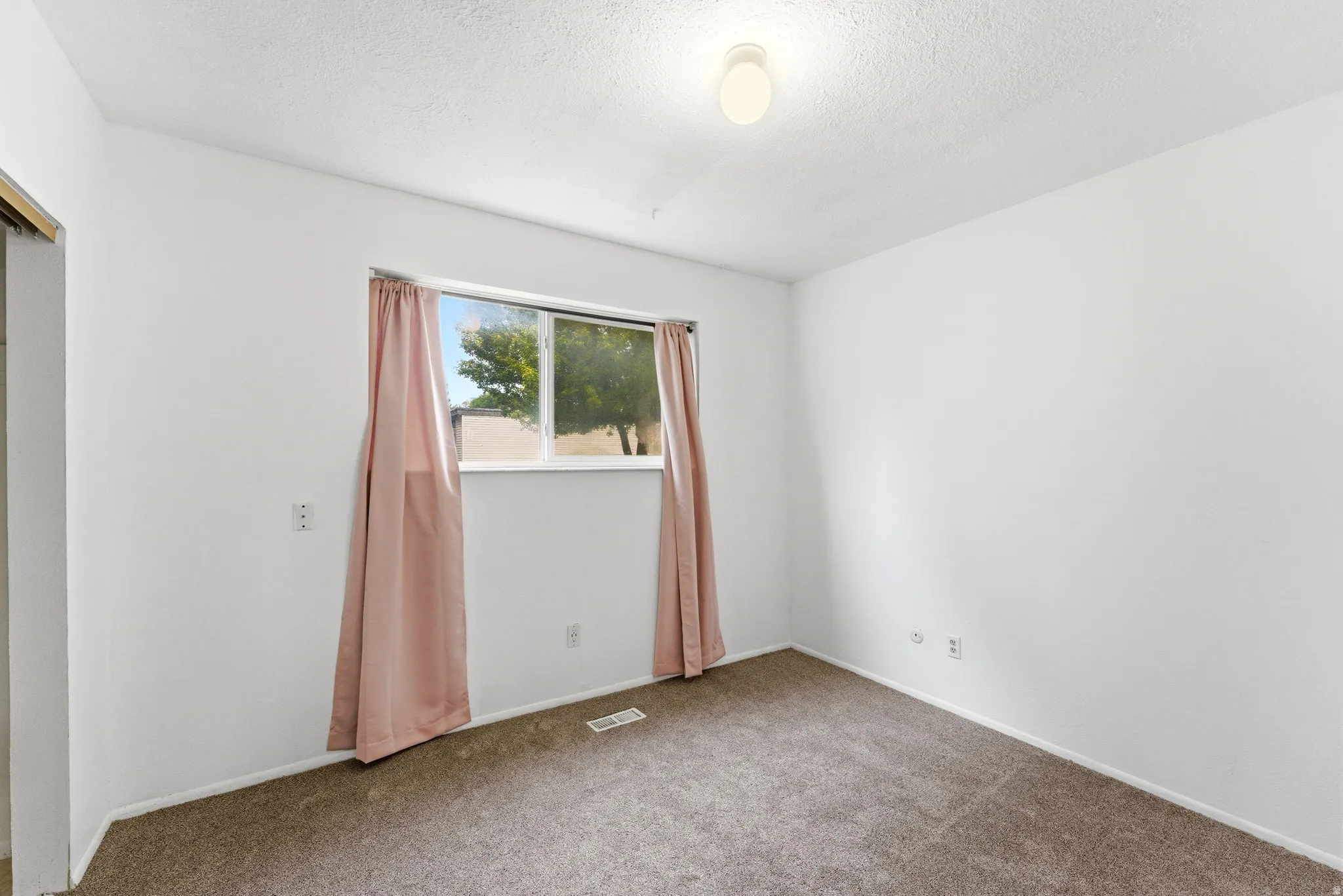 Carpeted room featuring a single window and white walls