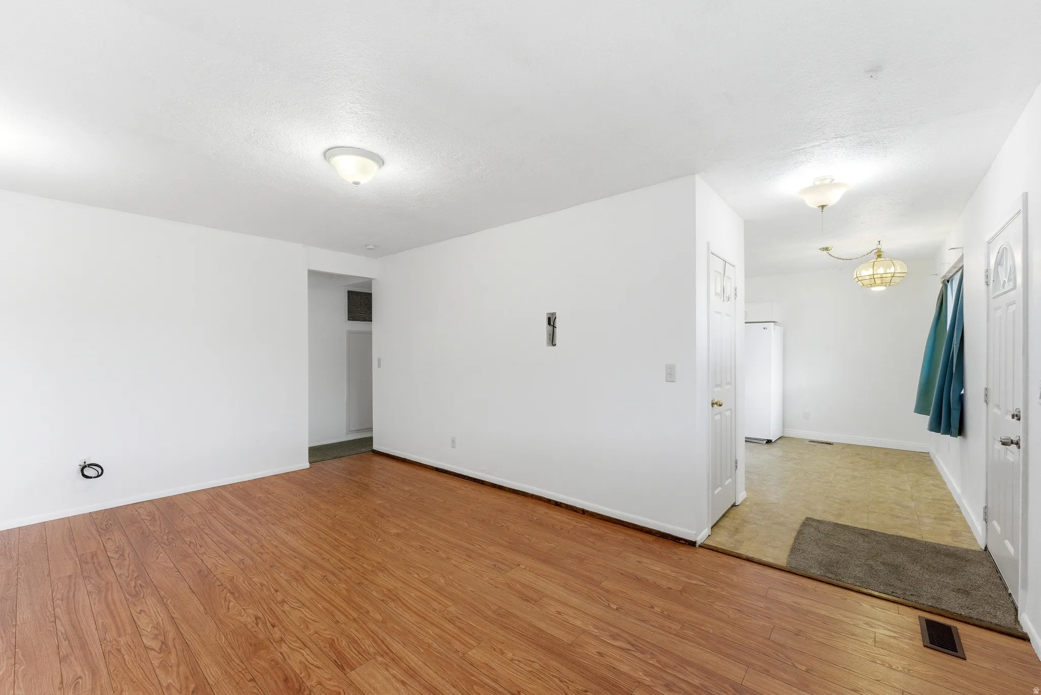 Spacious interior featuring wood-finish flooring, white walls, and a ceiling-mounted light fixture