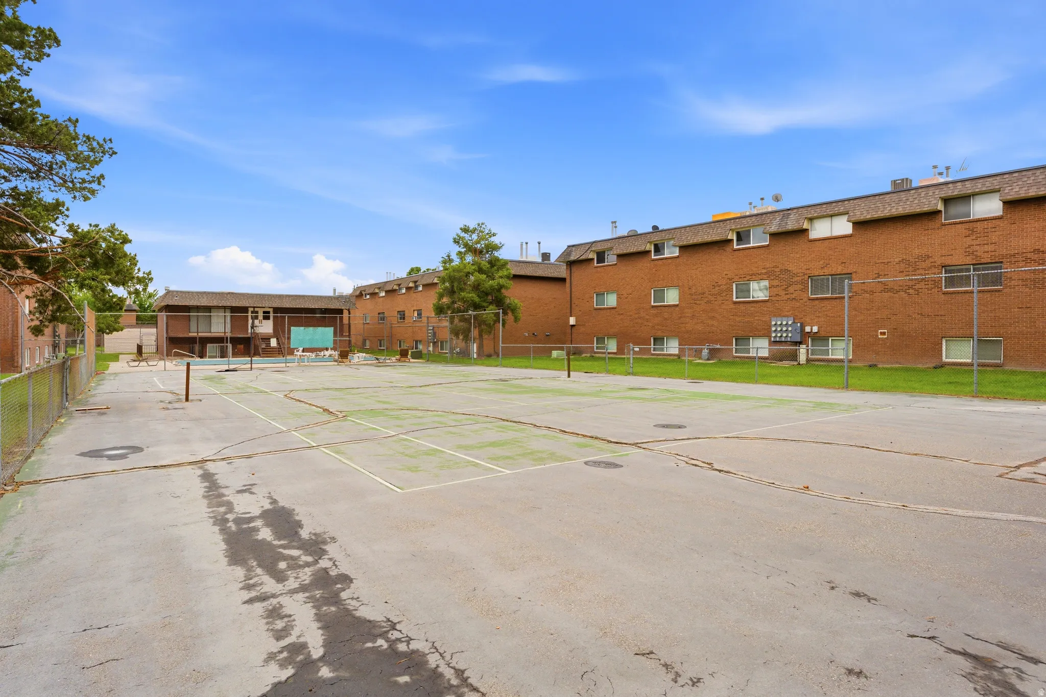 Outdoor recreation area featuring a hard-surface court with net posts and perimeter fencing