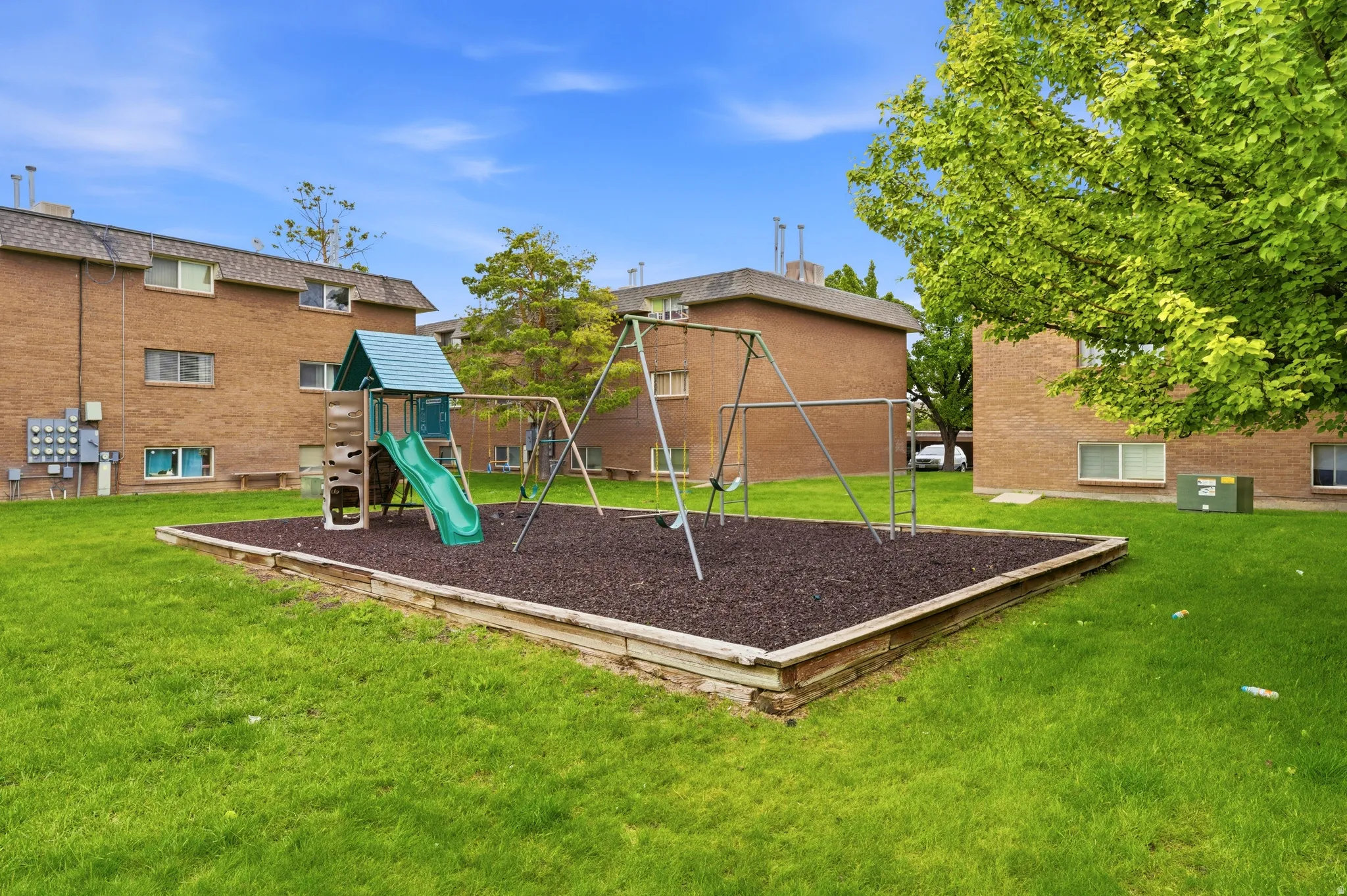 Outdoor recreation area featuring a play structure with a slide and swings