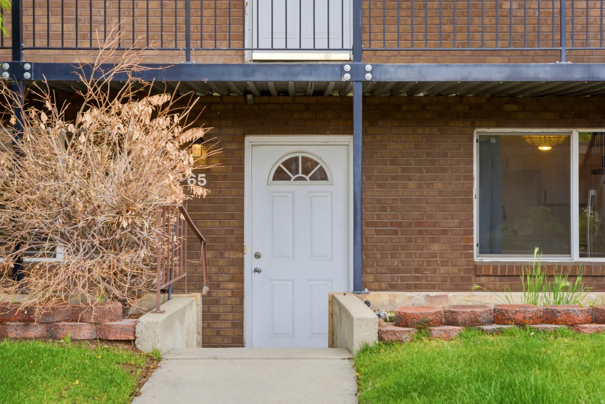 Brick exterior with a white entry door featuring an arched transom window