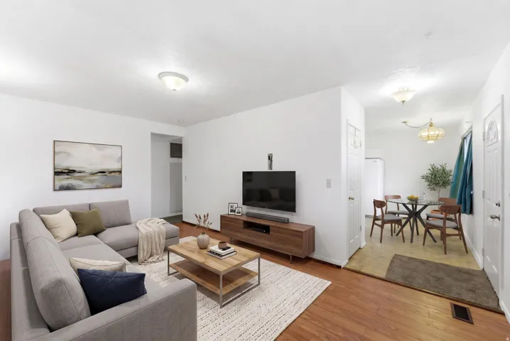 Open-concept living area with wood-finish flooring, white walls, and a recessed light fixture
