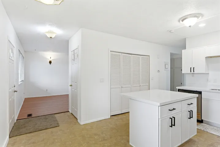 Contemporary kitchen island with white cabinetry, black hardware, and a solid surface countertop