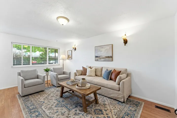Bright living room with wood-finish flooring, white walls, and a large window