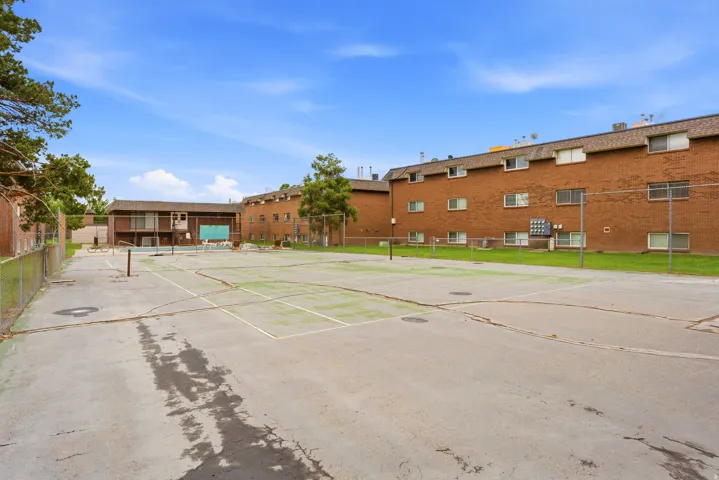 Outdoor recreation area featuring a hard-surface court with net posts and perimeter fencing