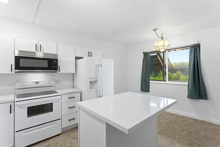 Bright kitchen with white cabinetry and a central island with a solid surface countertop