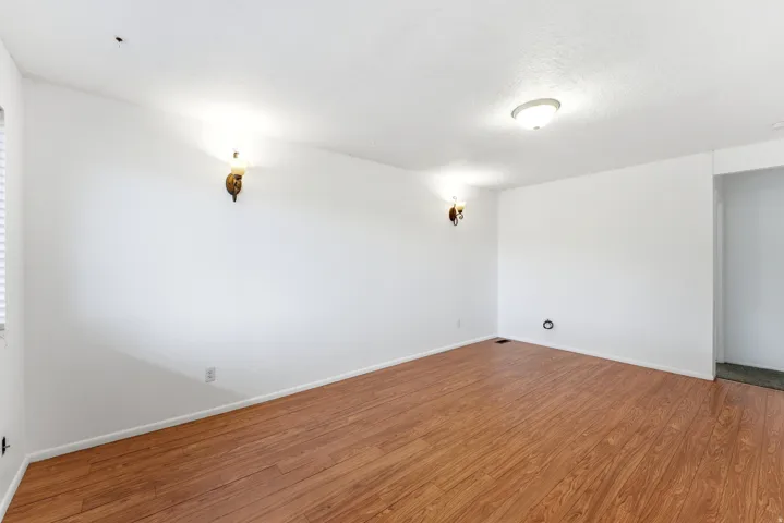 Spacious room featuring wood-finish flooring, white walls, and a white ceiling