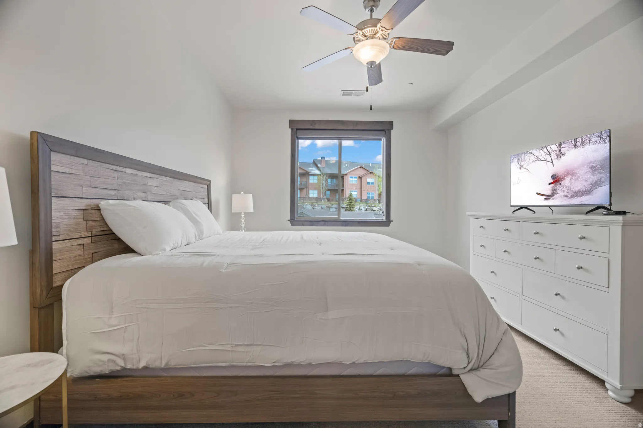 Window with dark wood trim, white walls, and a ceiling fan with integrated lighting
