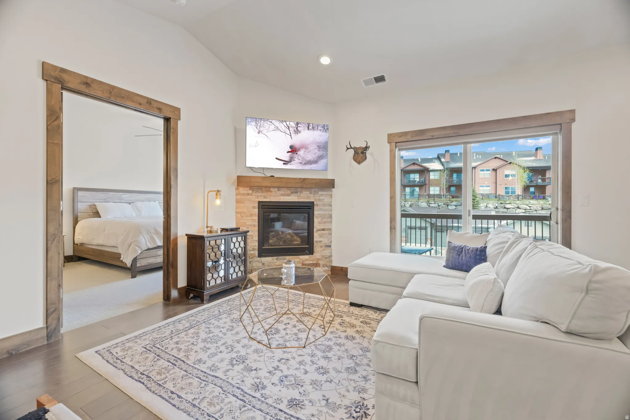 Living area featuring a stone-clad fireplace, dark wood-finish flooring, and a sliding glass door providing exterior access