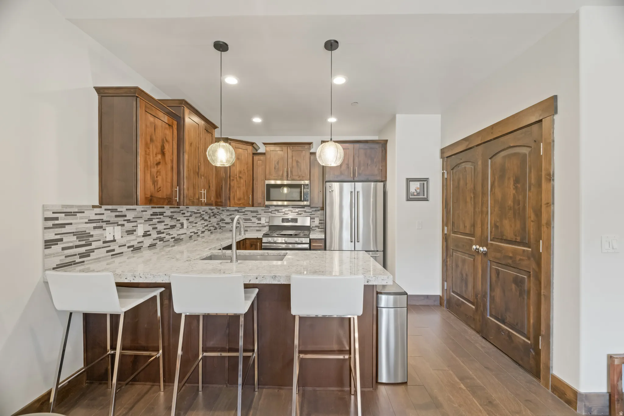 Kitchen featuring a granite-look countertop, mosaic tile backsplash, wood-finish cabinetry, and stainless steel appliances