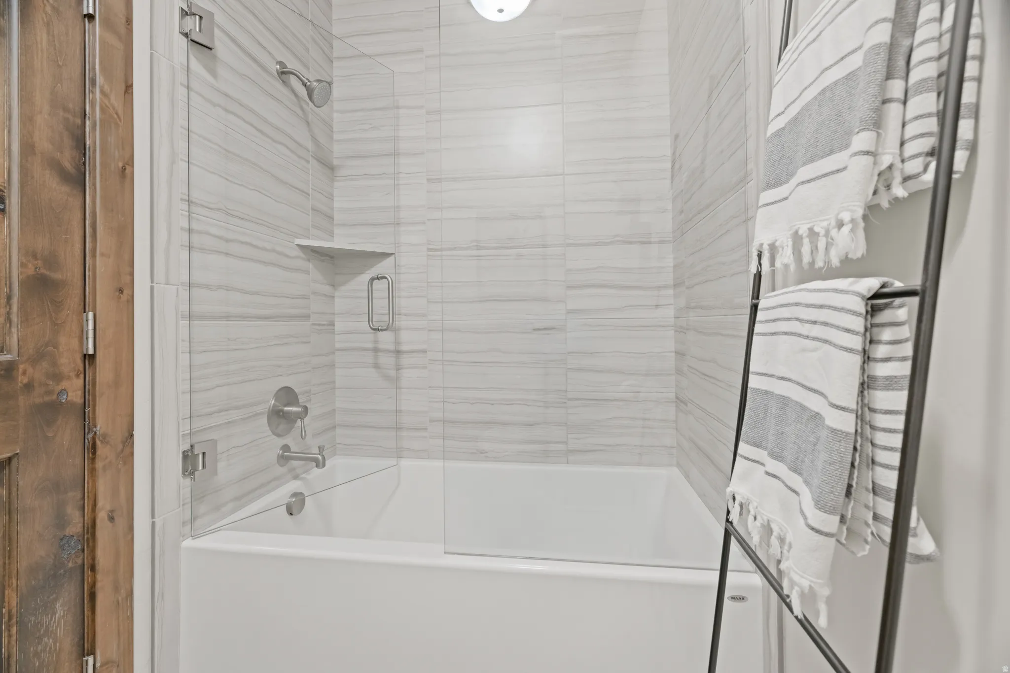 Full bath featuring a white tub, glass shower enclosure, and a tiled shower surround with an integrated corner shelf