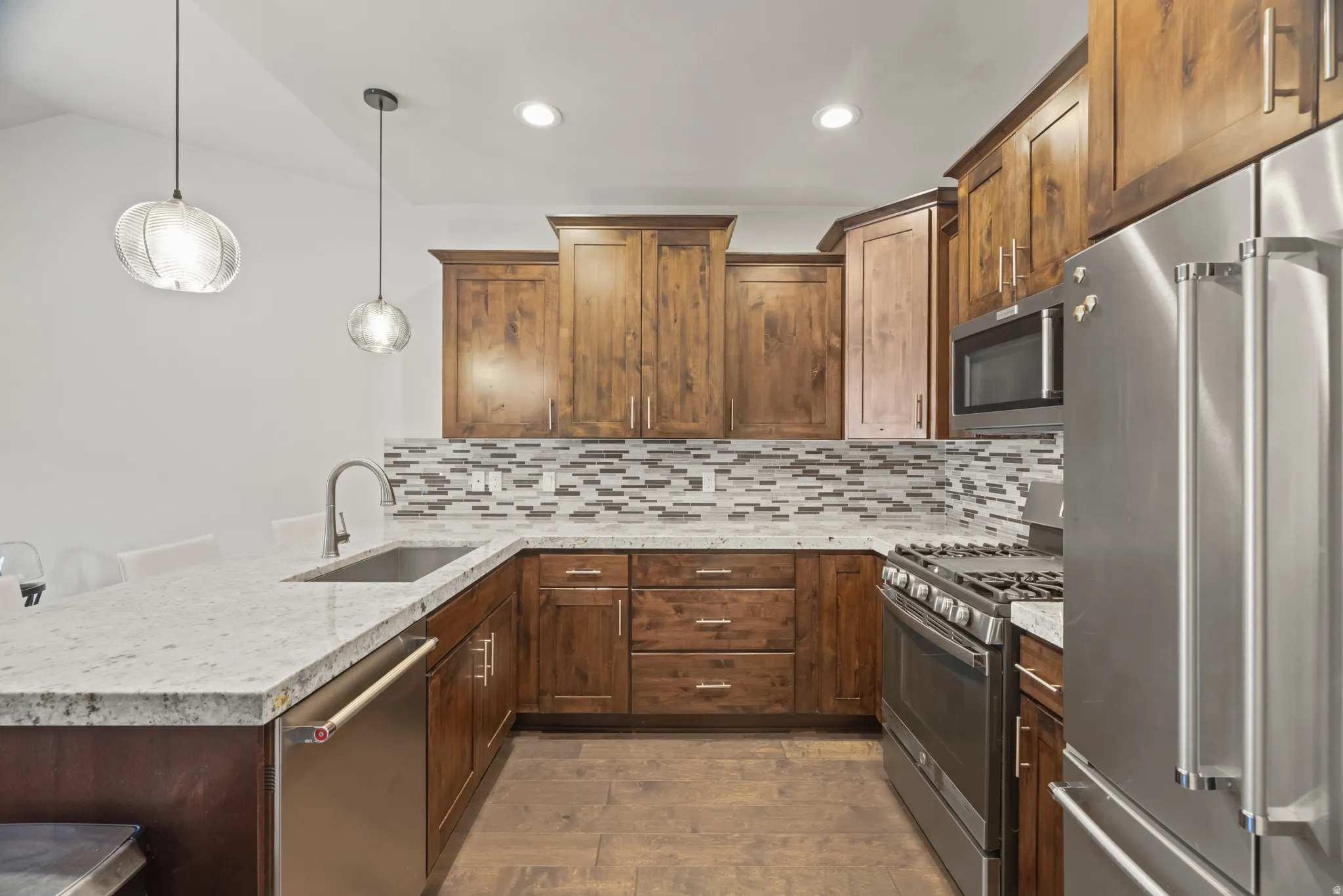 Modern kitchen featuring granite countertops, wood-finish flooring, and wood cabinetry