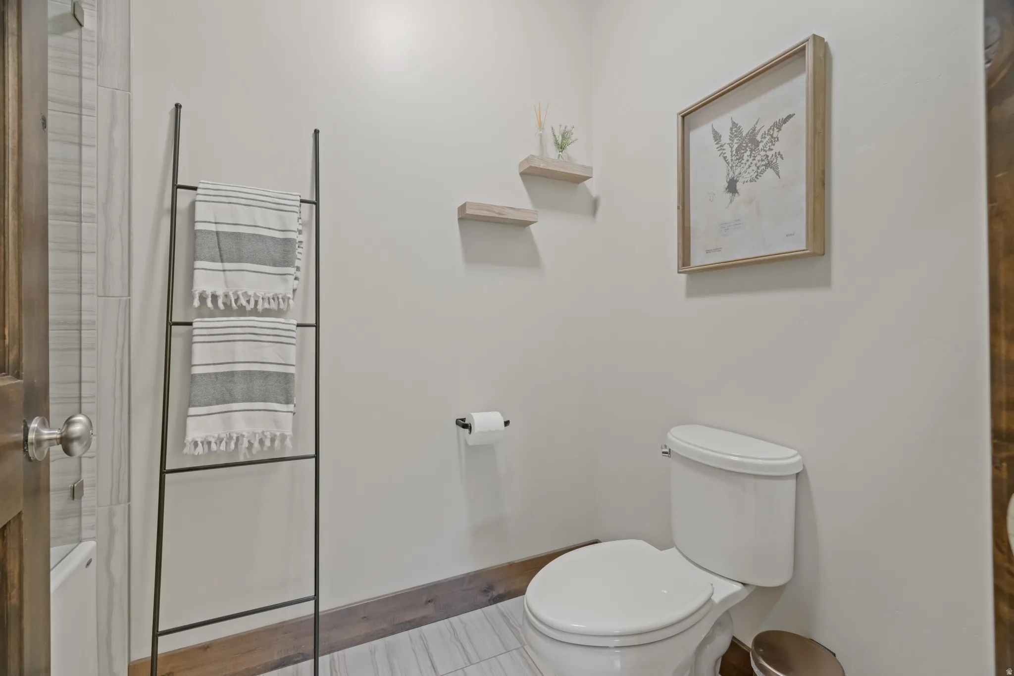 Powder room featuring a white toilet, light gray wall paint, and wood-finish baseboards