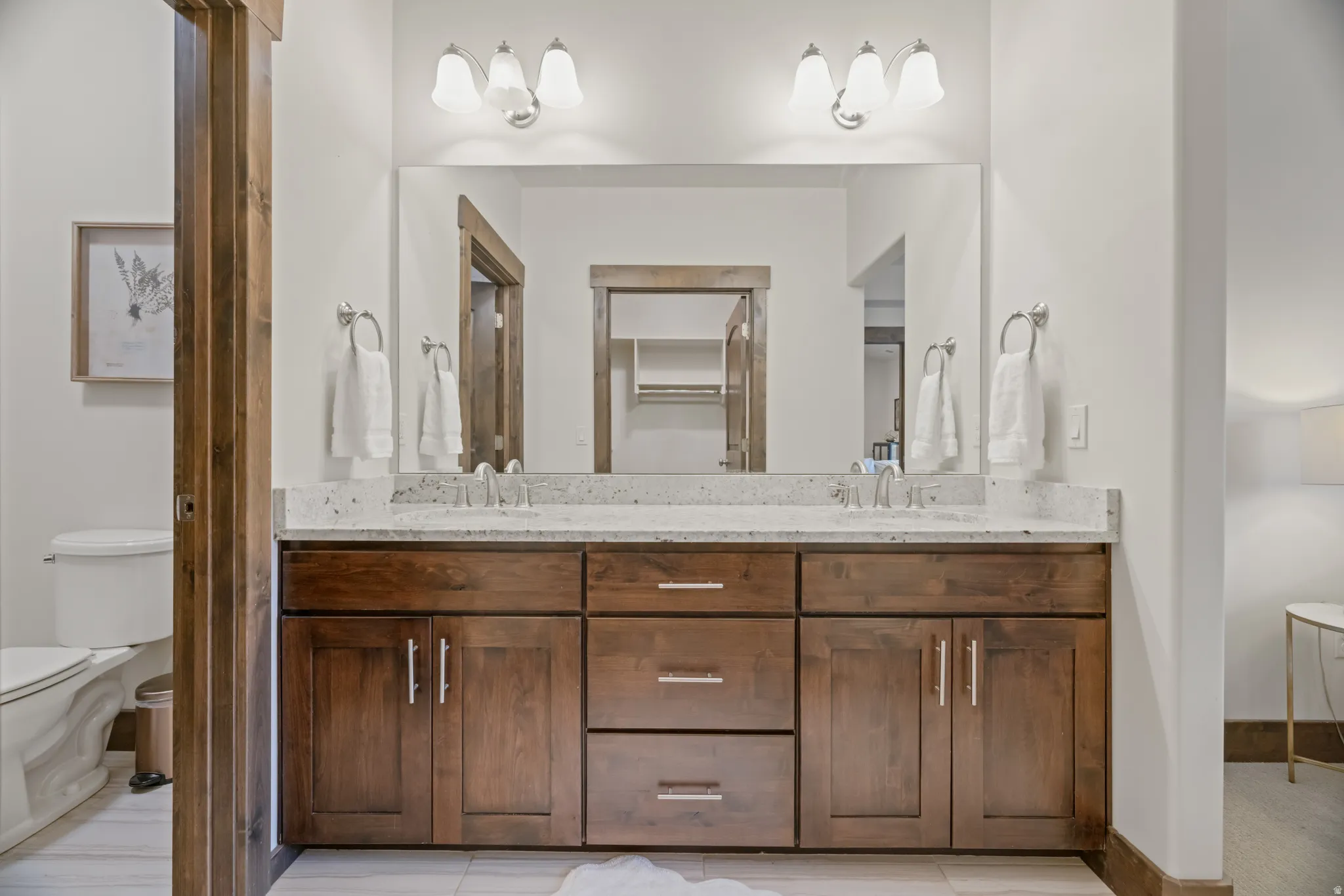 Dual vanity with wood-finish cabinetry, light-toned countertop, and dual sinks