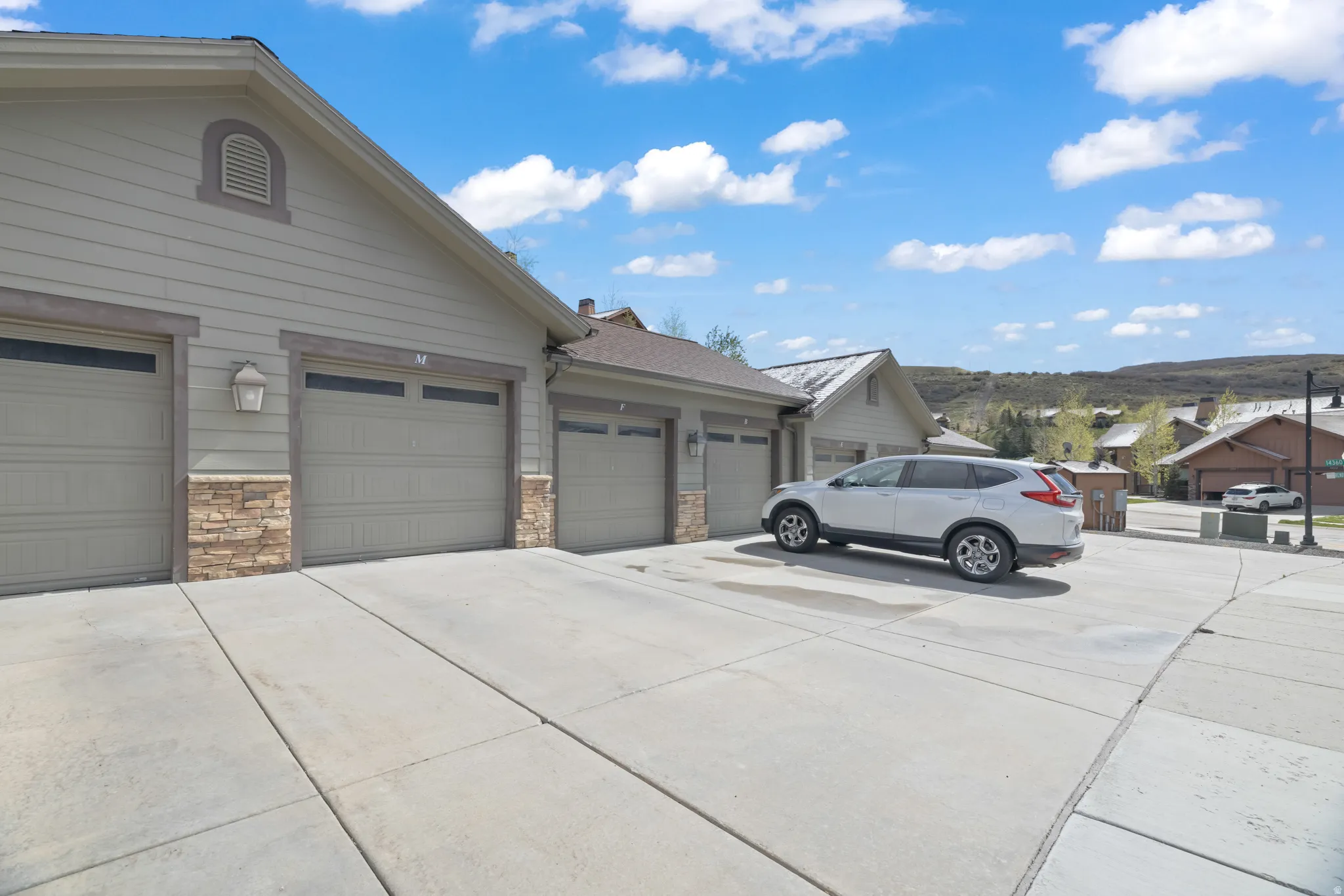 Three garage doors featuring integrated windows and stone veneer accents