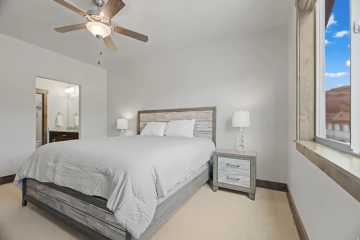 Neutral toned bedroom featuring a wood-finish ceiling fan and a window with wood trim