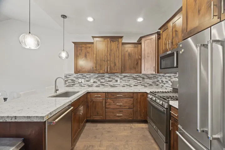 Modern kitchen featuring granite countertops, wood-finish flooring, and wood cabinetry