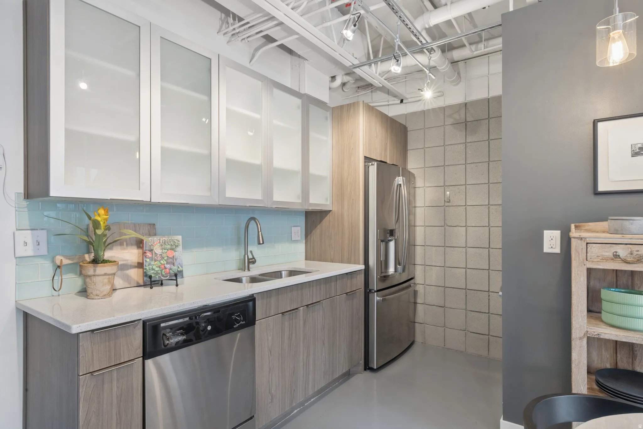 Kitchen featuring wood-finish cabinetry, stainless steel appliances, a tile backsplash, light countertops, and track lighting