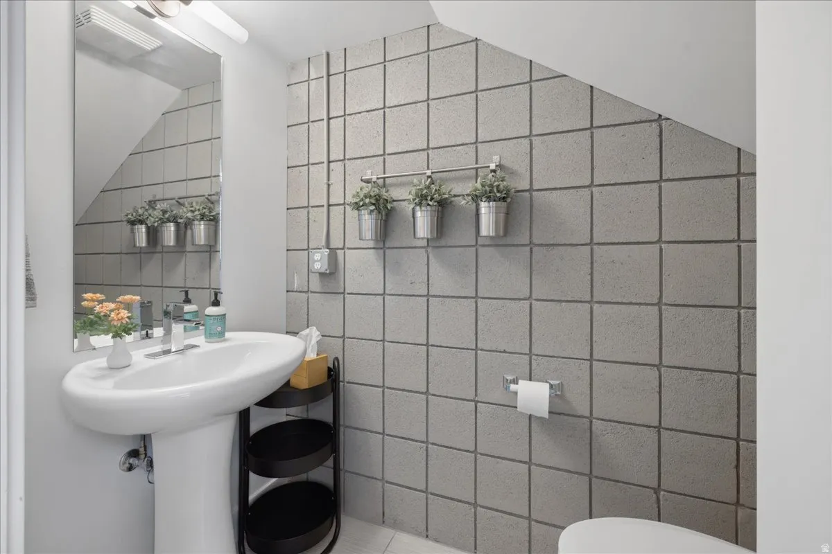 Pedestal sink with a polished chrome faucet and frameless wall-mounted mirror