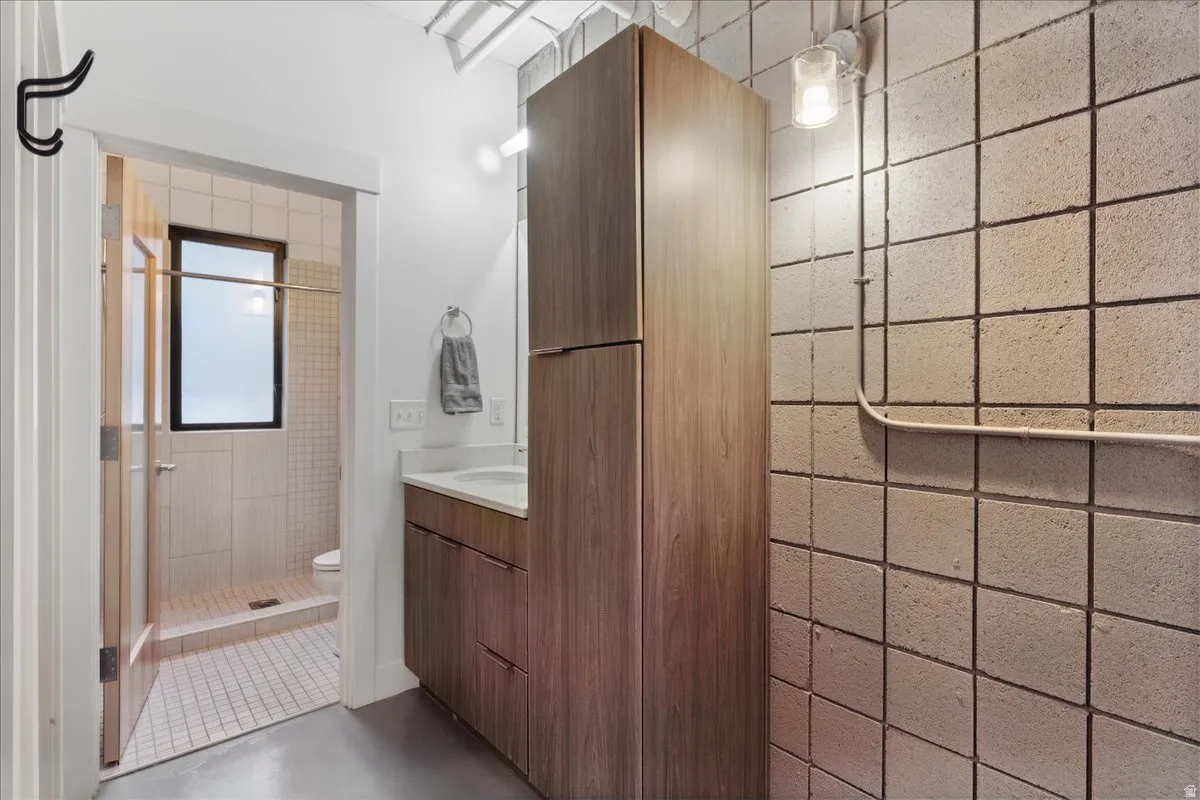 Bathroom featuring a wood-finish vanity with an integrated sink and a full-height storage cabinet