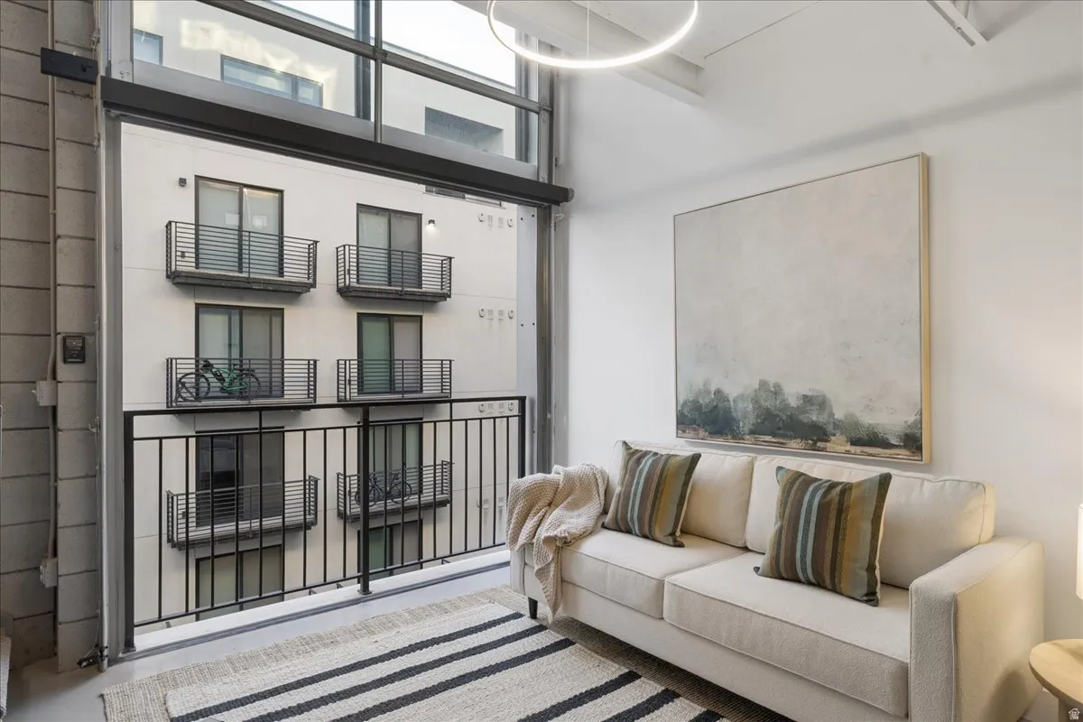 Spacious living area featuring high ceilings, a full-height glass wall, and a large balcony with black metal railings