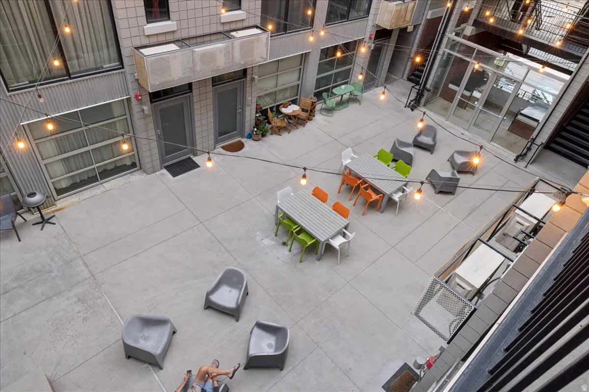 Expansive concrete courtyard featuring string lighting, multiple seating areas, and direct property access