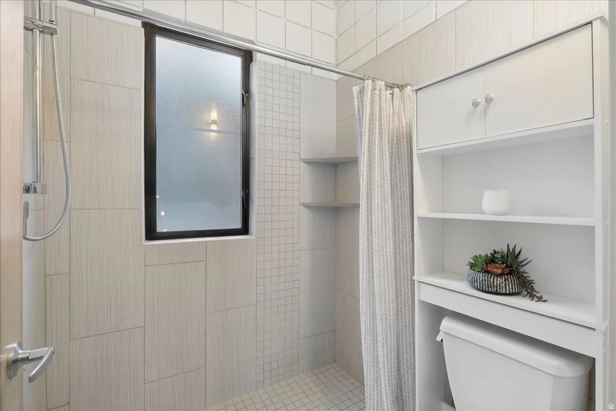 Shower with textured tile walls, a frosted window, and a built-in shower niche