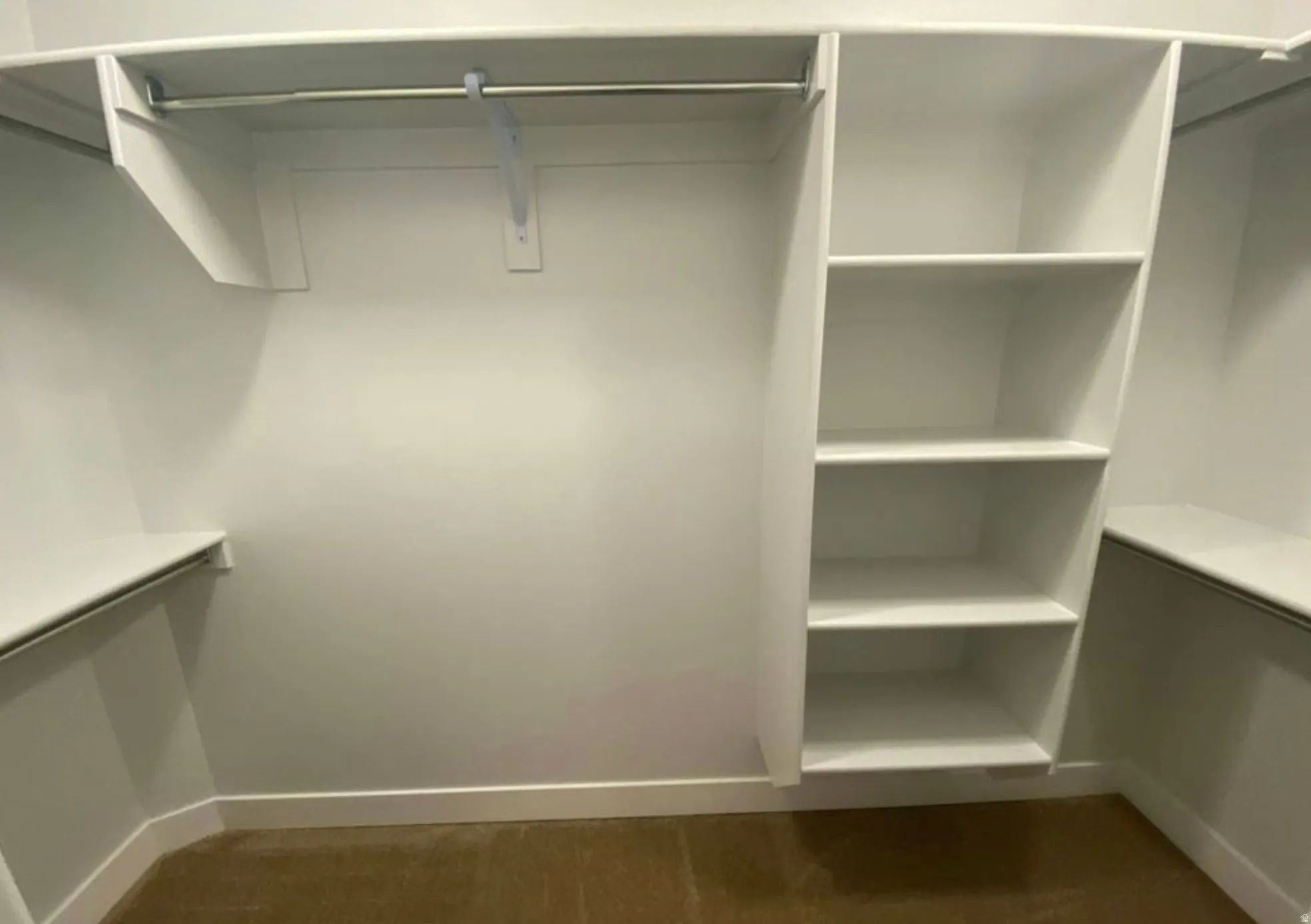 Walk-in closet featuring built-in shelving, hanging rods, white walls, and a carpeted floor