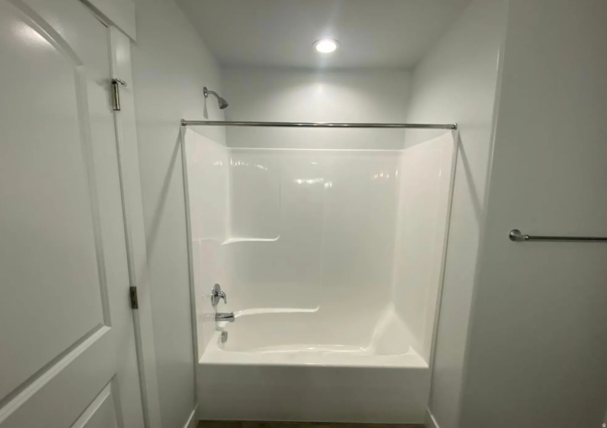 White fiberglass tub and shower combination with chrome fixtures and shower rod
