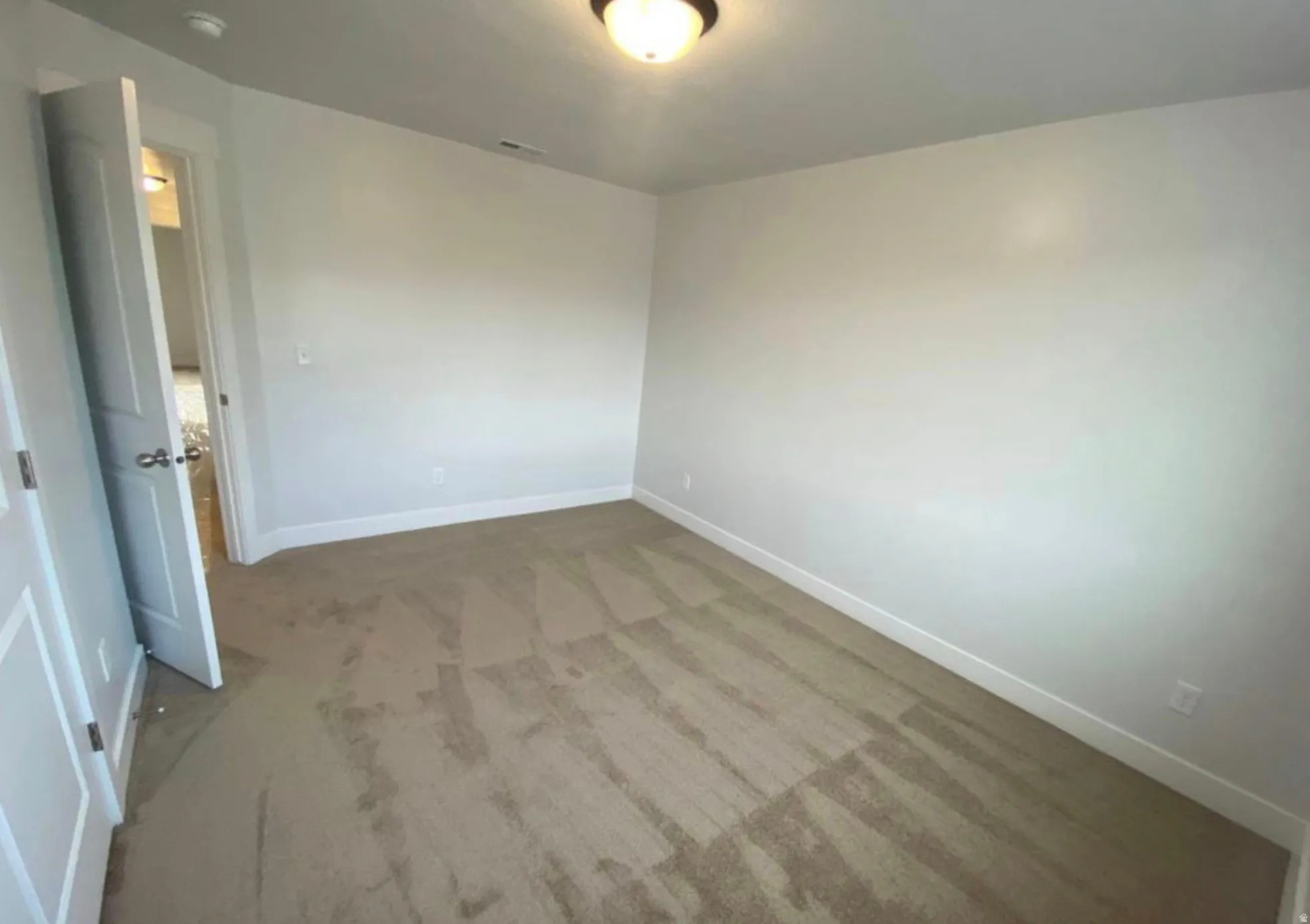 Interior room featuring light-toned walls, neutral carpet flooring, and white trim