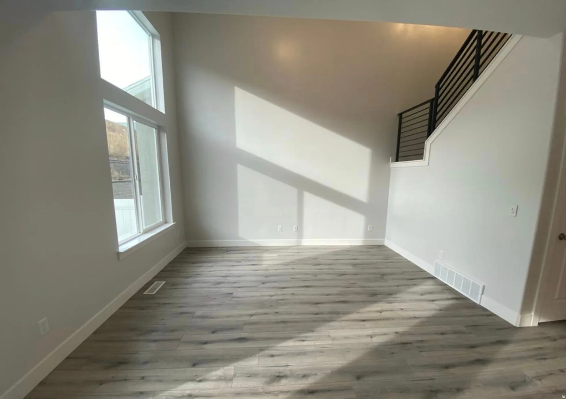 Spacious interior featuring a two-story window array, light-toned walls, and wood-finish flooring