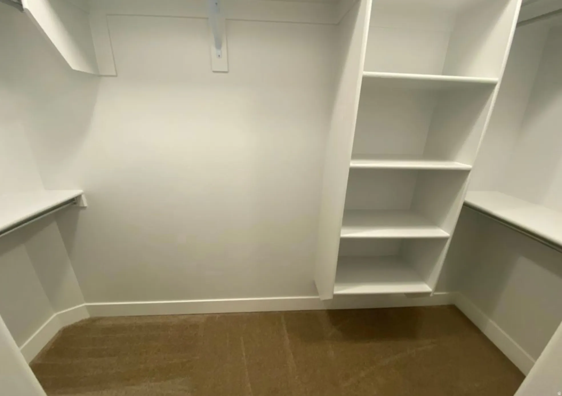 Walk-in closet featuring built-in shelving, multiple hanging rods, and neutral-toned carpeting