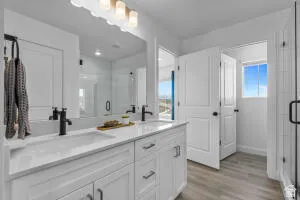 Double vanity featuring white cabinetry with brushed nickel hardware and integrated sinks