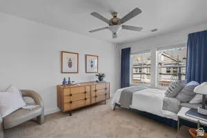 Bright bedroom featuring dual windows, ceiling fan with integrated lighting, and neutral carpeting