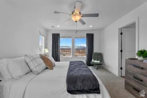Spacious bedroom featuring light neutral wall paint, recessed lighting, a ceiling fan fixture, and two large windows with dark drapery