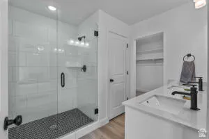 Bathroom featuring a glass-enclosed shower with white subway tile walls and dark mosaic floor, dual vanity with undermount sinks, and black fixtures