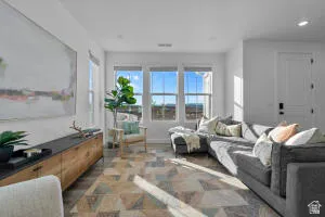Bright living area featuring multiple windows, wood-finish flooring, recessed lighting, and a white paneled door