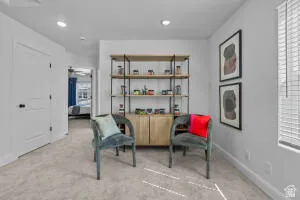 Carpeted room featuring a built-in shelving unit with lower wood-finish cabinetry, recessed lighting, and a window with blinds